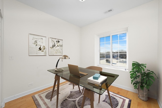 office area featuring baseboards, visible vents, and wood finished floors