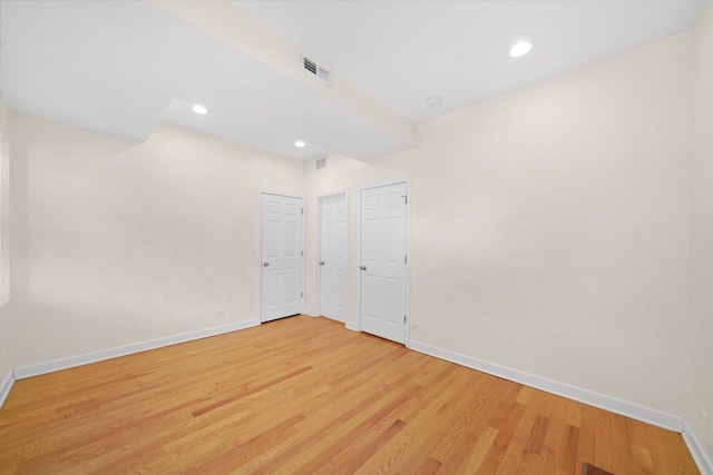 spare room featuring light wood-style floors, visible vents, and baseboards