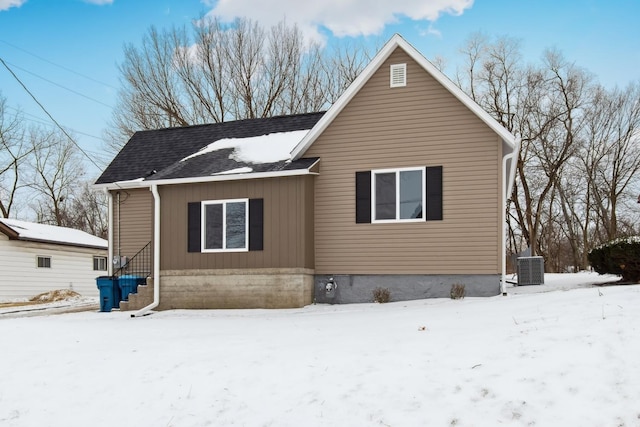 snow covered rear of property featuring central air condition unit