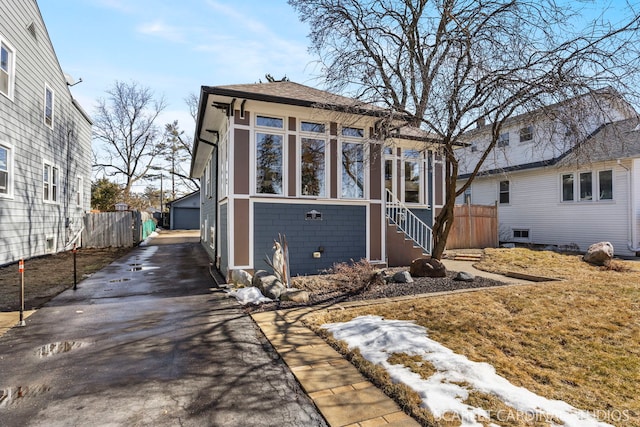 view of front facade featuring an outbuilding, a detached garage, and fence