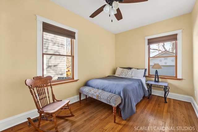 bedroom with a ceiling fan, visible vents, baseboards, and hardwood / wood-style flooring