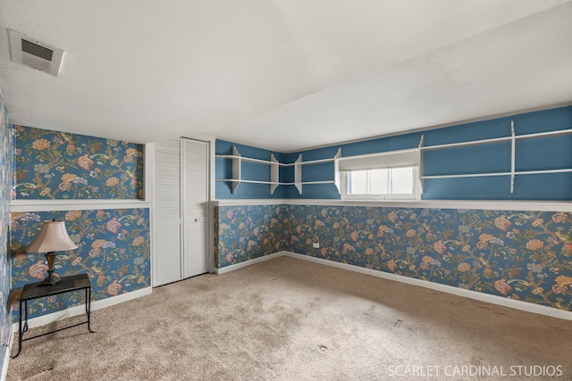 carpeted empty room featuring wallpapered walls, baseboards, and visible vents