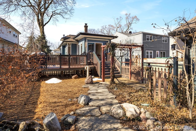 view of front of house featuring a chimney, fence, and a wooden deck