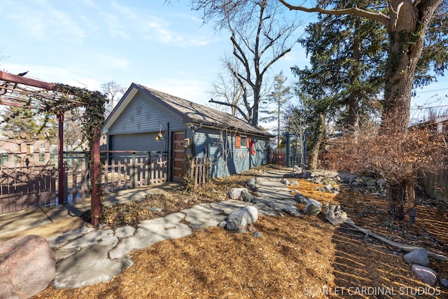 exterior space featuring a garage, an outdoor structure, and fence