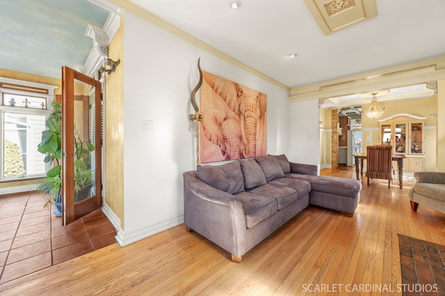 living area with baseboards, crown molding, and light wood finished floors