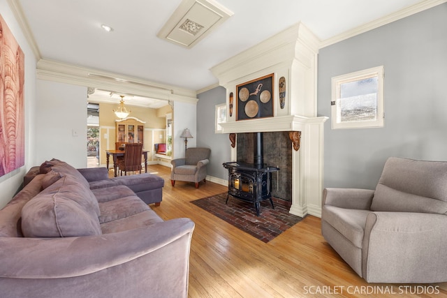 living room with light wood-style floors, a wood stove, crown molding, and baseboards