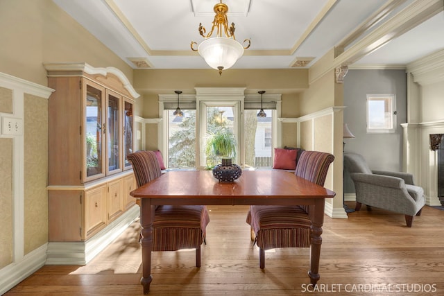 dining room featuring ornamental molding, a raised ceiling, light wood-style flooring, and baseboards