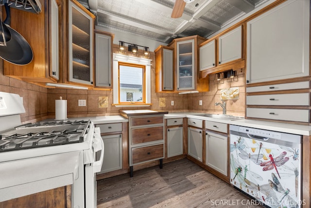 kitchen featuring decorative backsplash, dishwashing machine, white gas range, light wood-style floors, and a sink