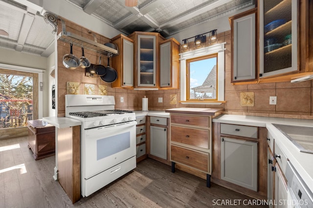 kitchen with white gas range oven, backsplash, wood finished floors, and light countertops