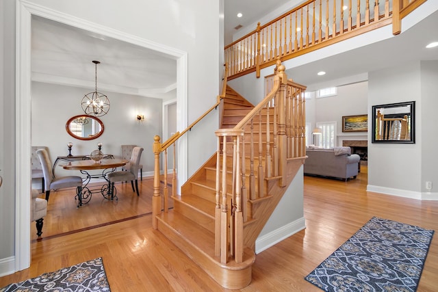 stairs featuring hardwood / wood-style flooring, a towering ceiling, and an inviting chandelier