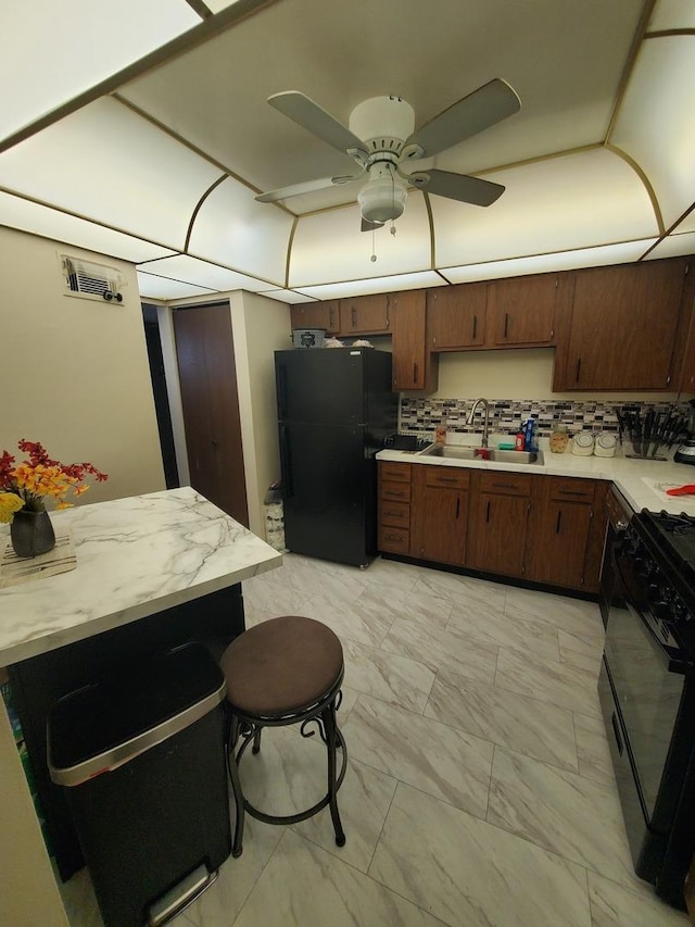 kitchen with a breakfast bar, sink, backsplash, ceiling fan, and black appliances