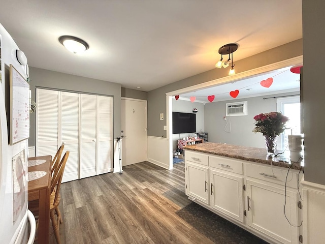 kitchen with a wall mounted AC, dark hardwood / wood-style floors, and white cabinets