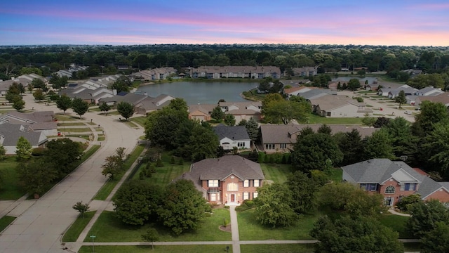 aerial view at dusk featuring a water view and a residential view