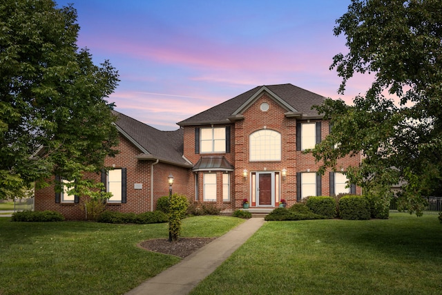 view of front of house with brick siding, a shingled roof, and a front yard