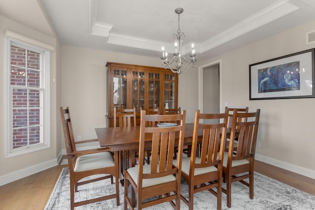 dining space featuring ornamental molding, wood finished floors, a raised ceiling, and baseboards