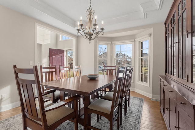 dining room featuring light wood-type flooring, a wealth of natural light, baseboards, and a tray ceiling