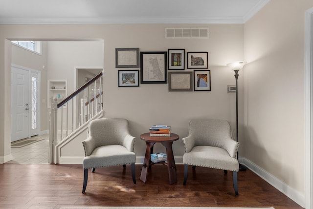 living area featuring baseboards, visible vents, wood finished floors, stairs, and crown molding