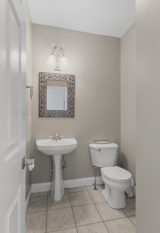 bathroom with tile patterned flooring, baseboards, a sink, and toilet