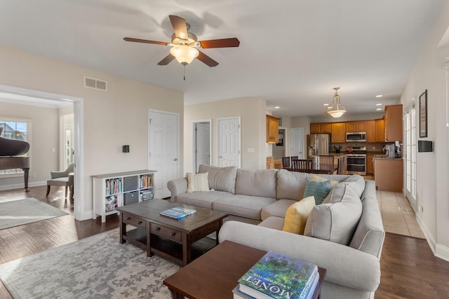 living room featuring visible vents, baseboards, and wood finished floors