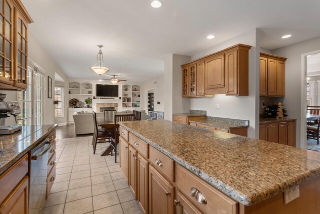 kitchen featuring built in shelves, light tile patterned flooring, open floor plan, stainless steel dishwasher, and a tiled fireplace