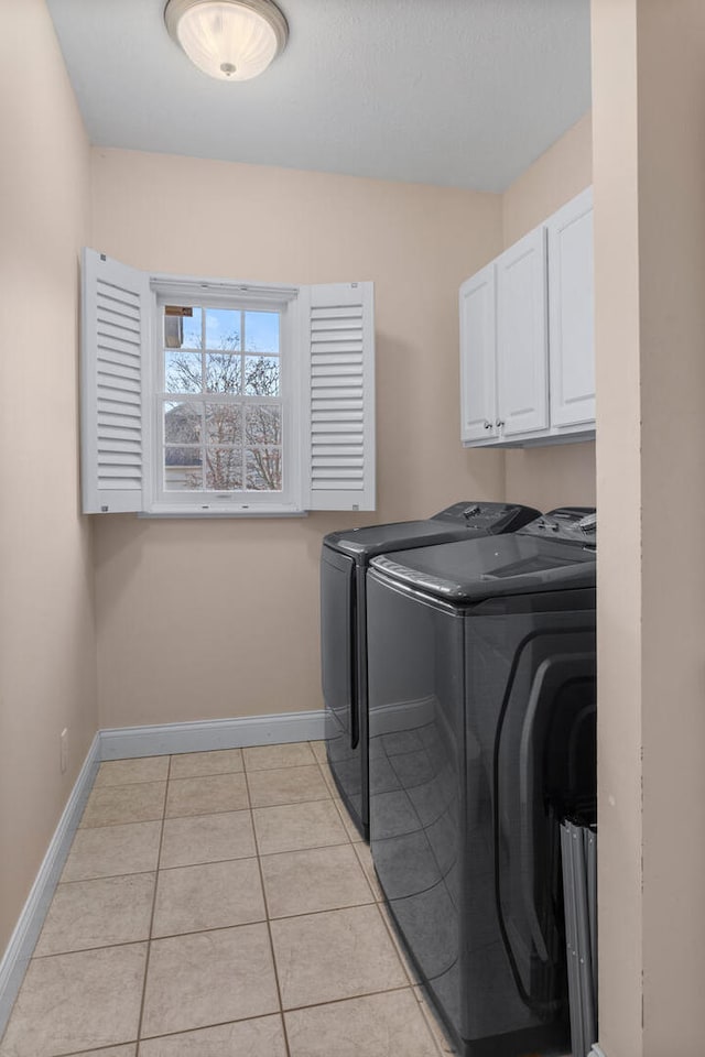 laundry area featuring cabinet space, light tile patterned floors, baseboards, and washer and dryer