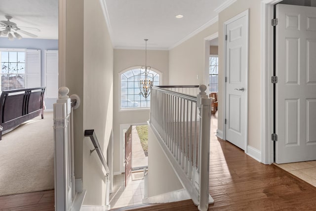 hall featuring a notable chandelier, ornamental molding, an upstairs landing, wood finished floors, and baseboards