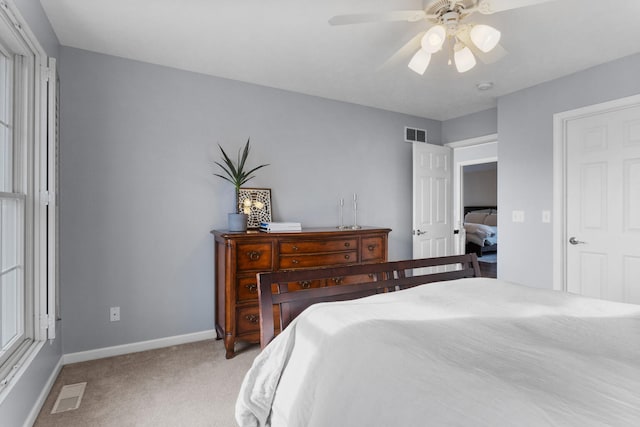 bedroom with a ceiling fan, light colored carpet, visible vents, and baseboards