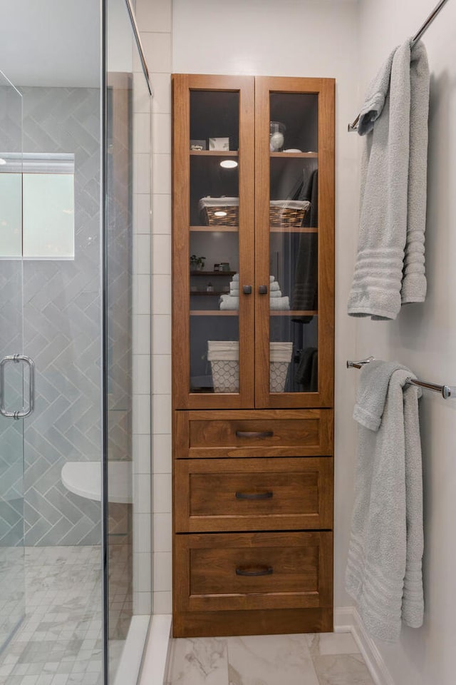 bathroom with a stall shower and marble finish floor