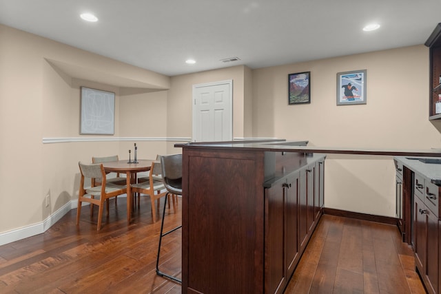 kitchen with visible vents, dark wood finished floors, a kitchen bar, and dark brown cabinets