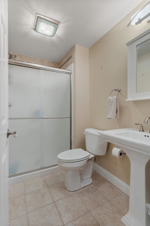 full bath with a textured ceiling, toilet, baseboards, a shower stall, and tile patterned floors