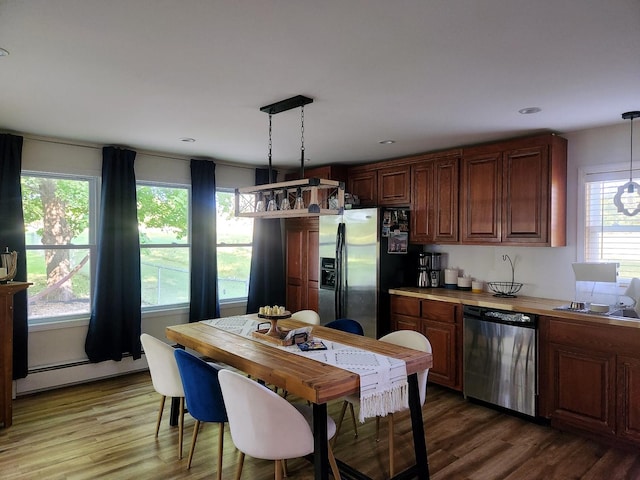 kitchen featuring pendant lighting, a baseboard radiator, wood-type flooring, and appliances with stainless steel finishes