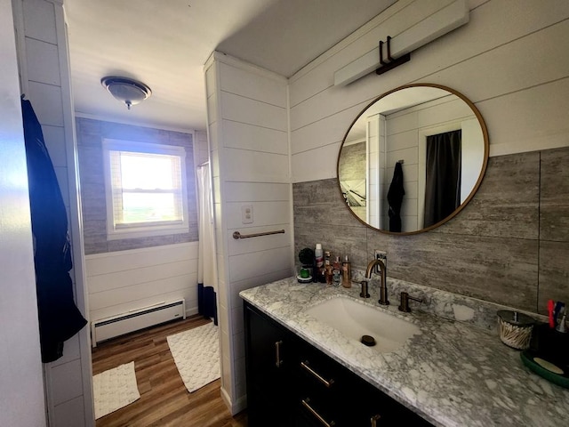 bathroom featuring vanity, a baseboard heating unit, wood-type flooring, and wooden walls