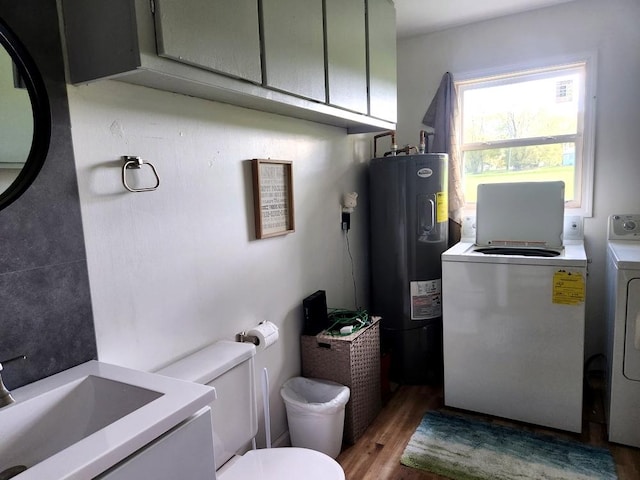 bathroom with hardwood / wood-style floors, sink, toilet, electric water heater, and washer and clothes dryer