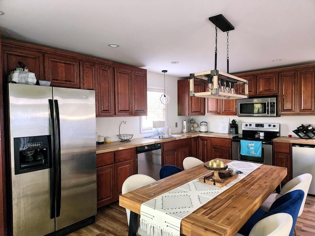 kitchen featuring stainless steel appliances, dark hardwood / wood-style flooring, sink, and hanging light fixtures