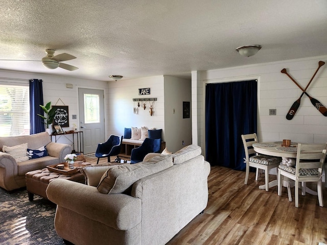 living room with ceiling fan, dark wood-type flooring, and a textured ceiling