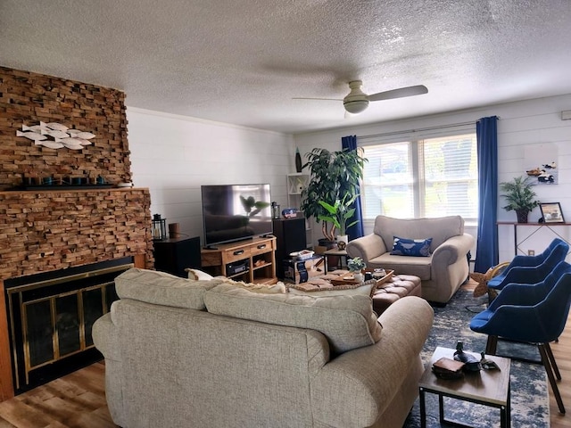 living room with wood-type flooring, a large fireplace, and a textured ceiling