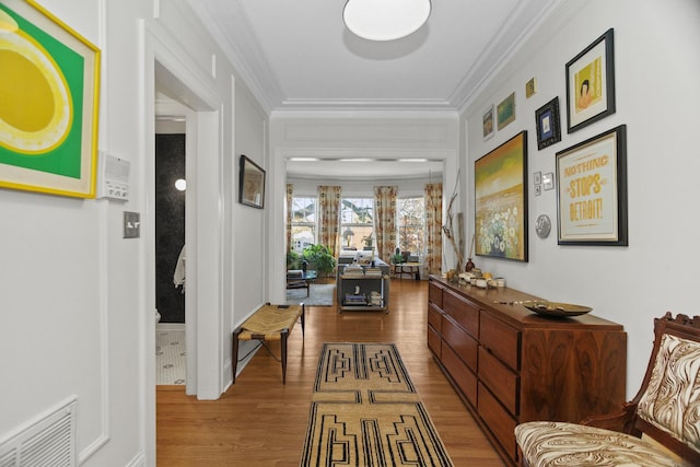 hallway featuring visible vents, wood finished floors, and ornamental molding