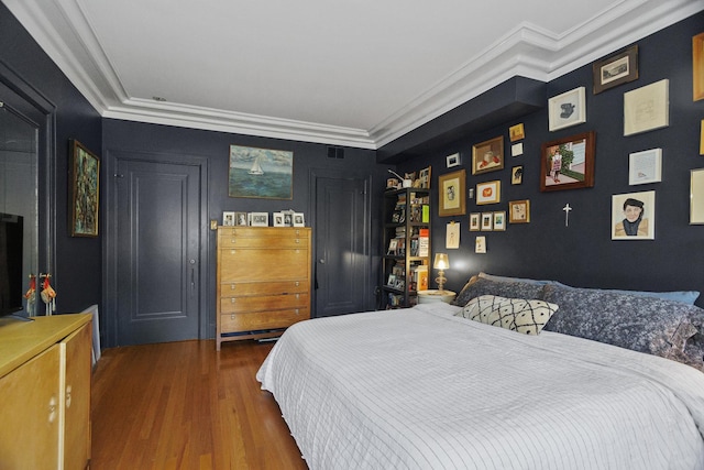 bedroom featuring ornamental molding, visible vents, and wood finished floors