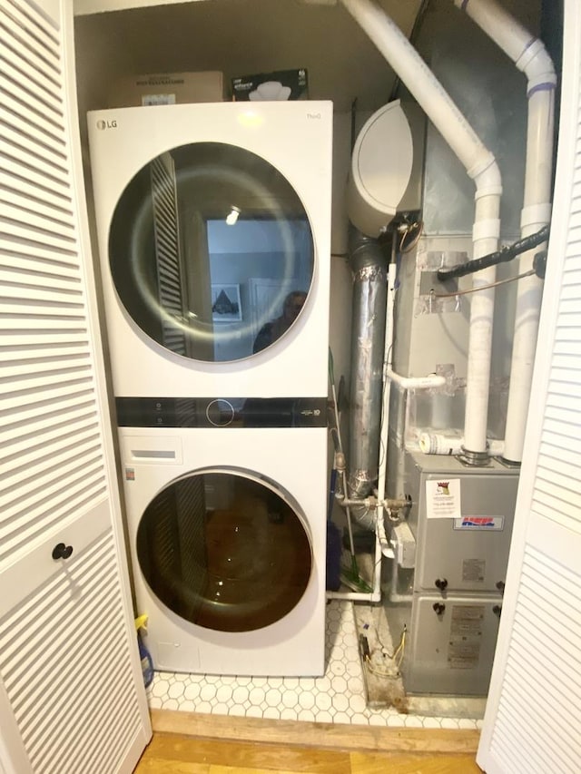 clothes washing area with stacked washer / drying machine, laundry area, and wood finished floors