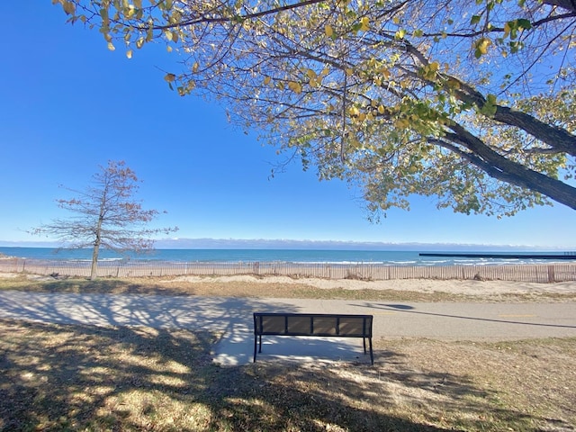 surrounding community with a water view, fence, and a beach view