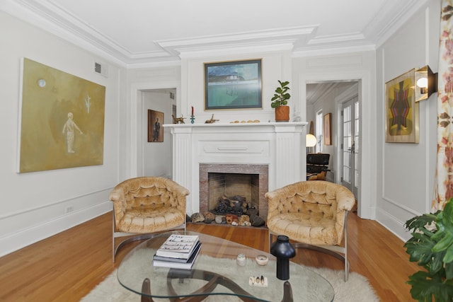 living area featuring a fireplace, visible vents, crown molding, and wood finished floors