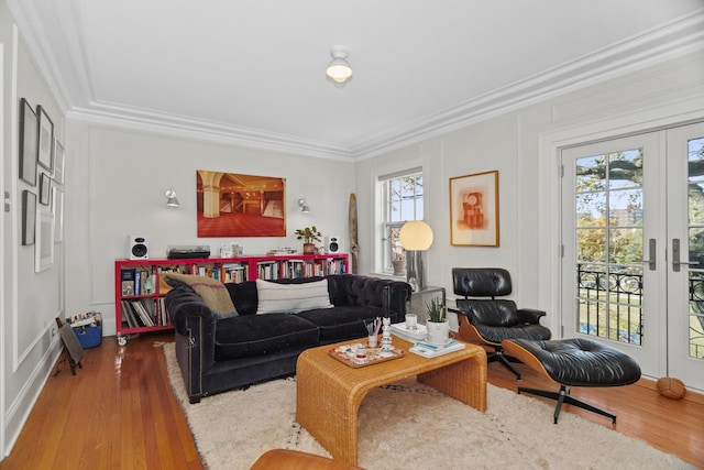 living area featuring french doors, a decorative wall, wood finished floors, and crown molding