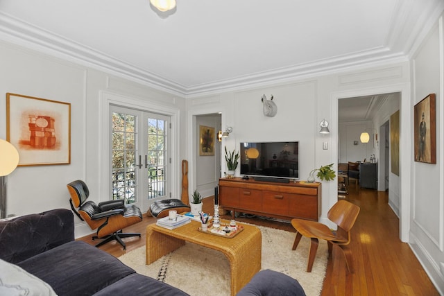 living room featuring ornamental molding, french doors, wood finished floors, and a decorative wall