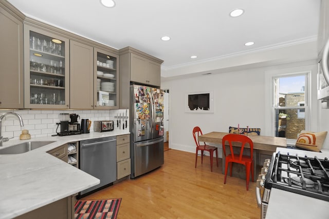 kitchen featuring a sink, gray cabinets, stainless steel appliances, light wood-type flooring, and backsplash