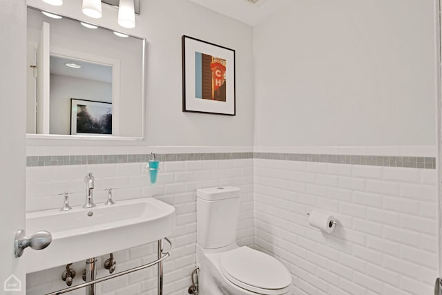 bathroom featuring tile walls, sink, and toilet