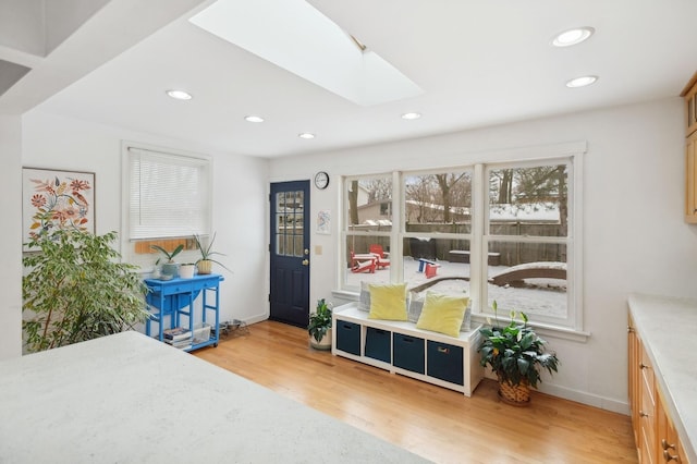 game room with a skylight and light hardwood / wood-style flooring