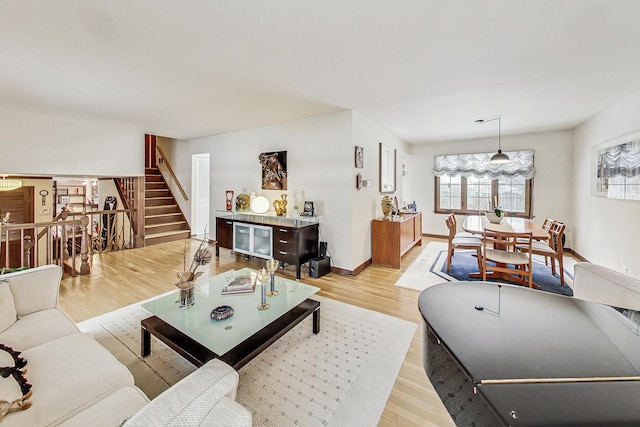 living room featuring stairway, light wood-style flooring, and baseboards