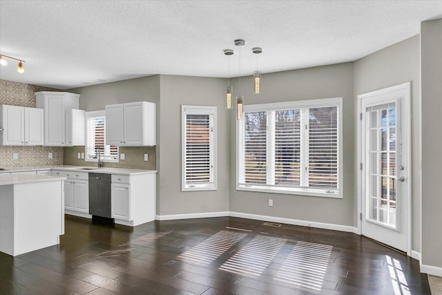 kitchen with white cabinets, light countertops, stainless steel dishwasher, and hanging light fixtures