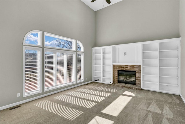 unfurnished living room with a fireplace, light colored carpet, a ceiling fan, high vaulted ceiling, and baseboards