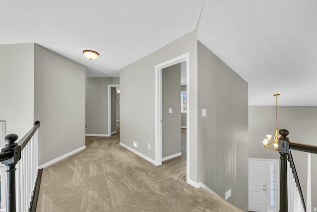 corridor with baseboards, light carpet, an upstairs landing, and an inviting chandelier